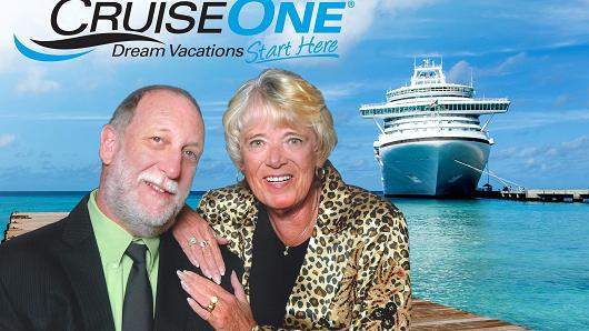 A couple posing for a picture with an ocean and cruise ship background.