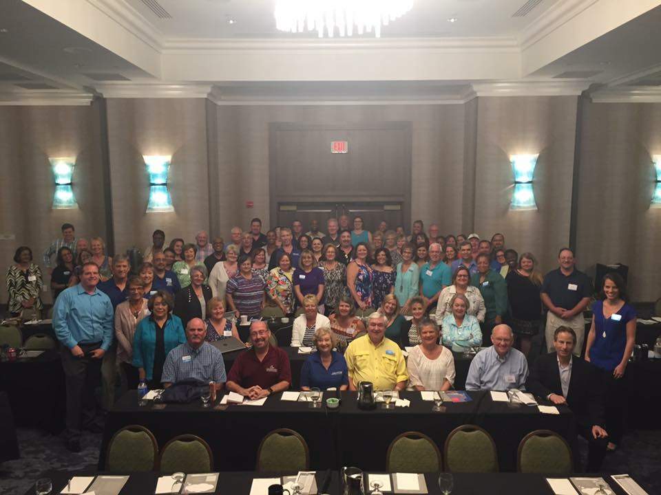 A large group of people gathered in a conference room for a photo.