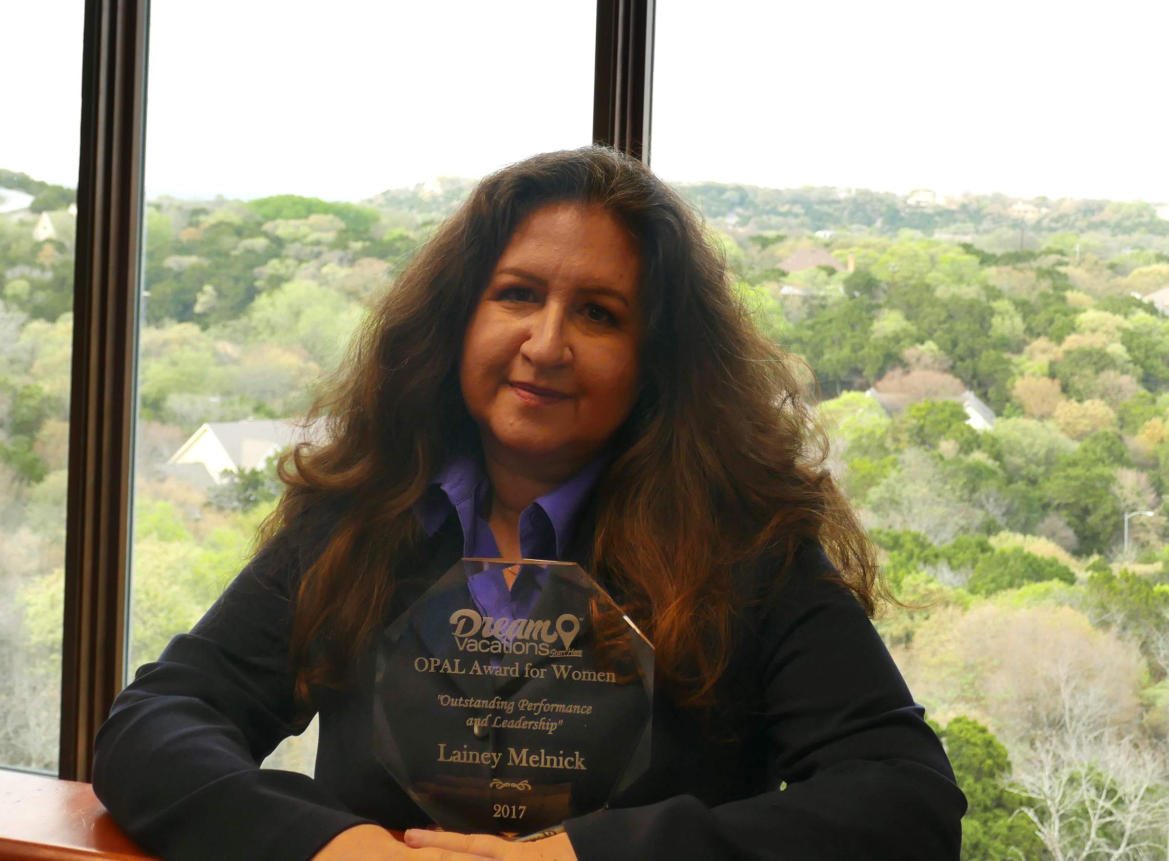 Woman posing with an award with mountainside in the distance.