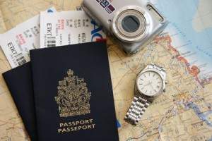 Plane tickets, passport, watch, camera lying on a large map.