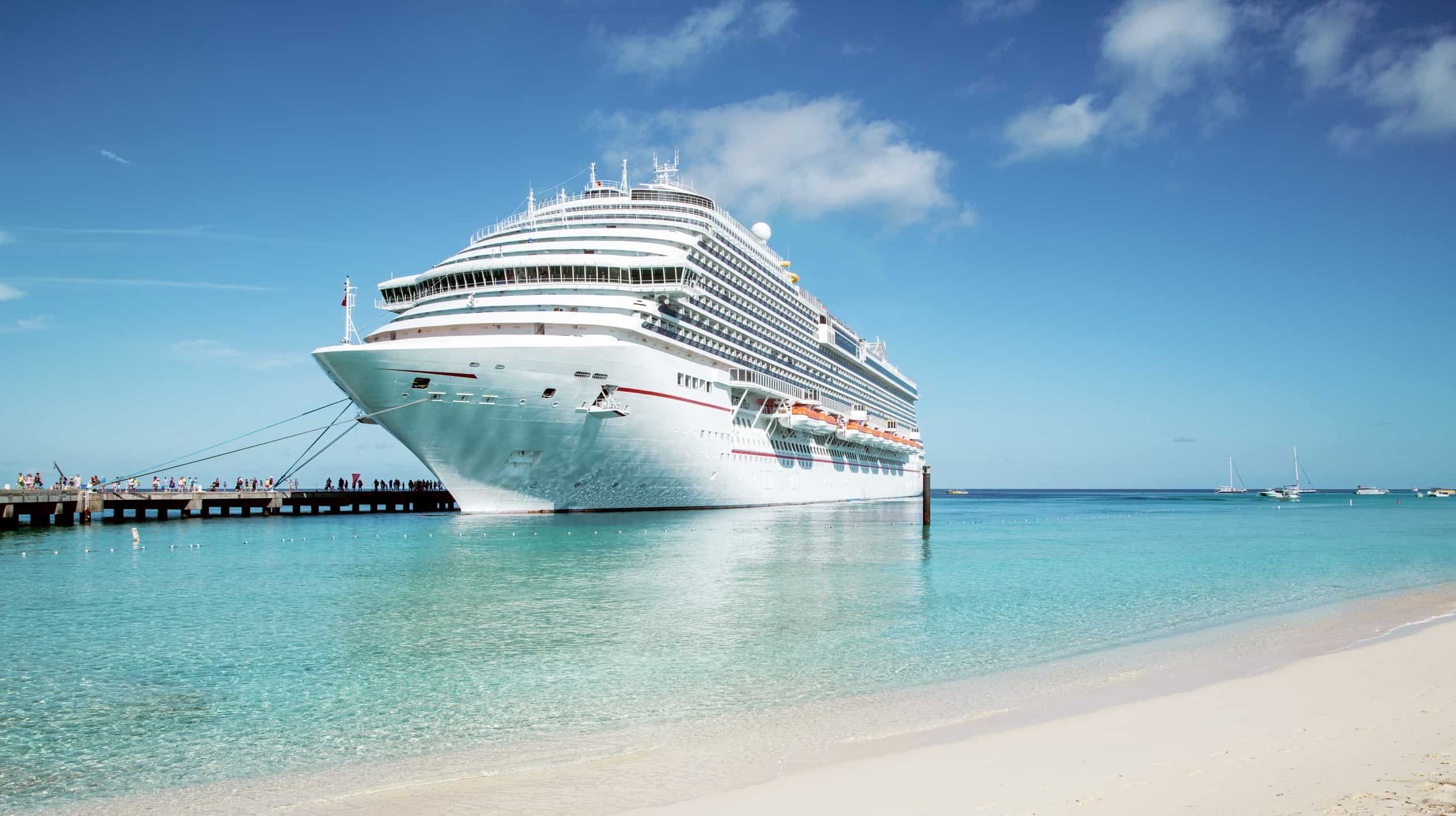 Cruise ship at dock of gorgeous beach with people boarding
