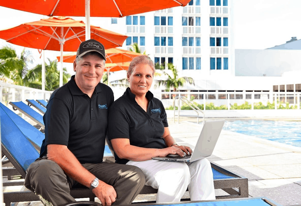 How does Dream Vacations Franchise work? Two franchisees work on a laptop beside a pool