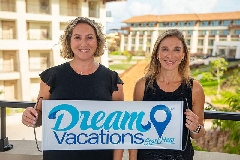 Two women holding a Dream Vacations sign.