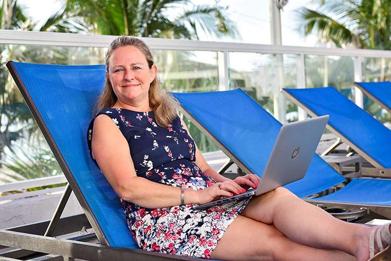 A Dream Vacations travel agent working poolside on her laptop