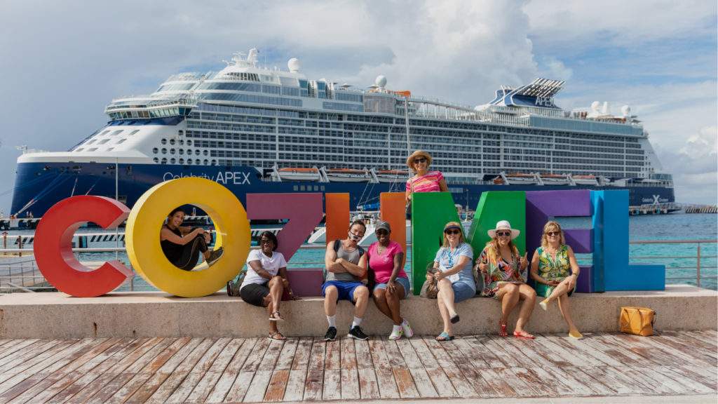 A group of people in front of a cruise ship