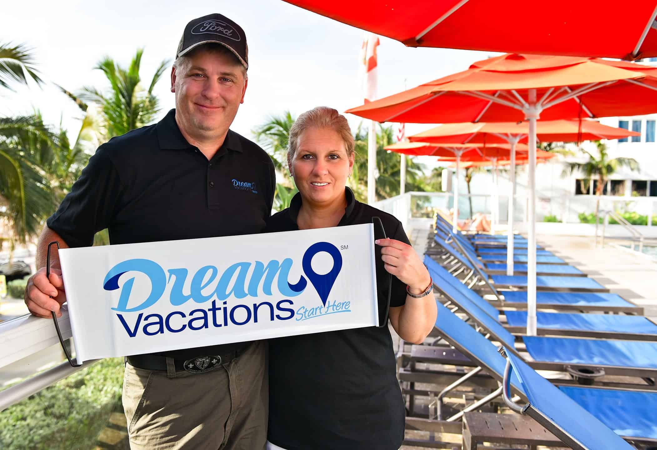 Team members holding a Dream Vacations banner -- learn how to start your own travel agency