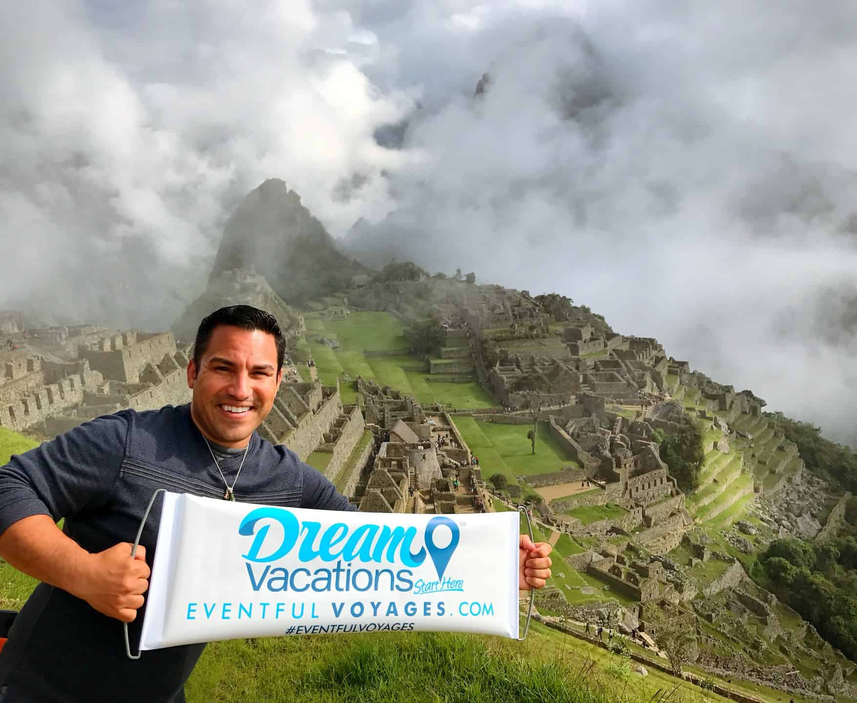 Eddie Diaz holding a Dream Vacations banner at Macchu Picchu