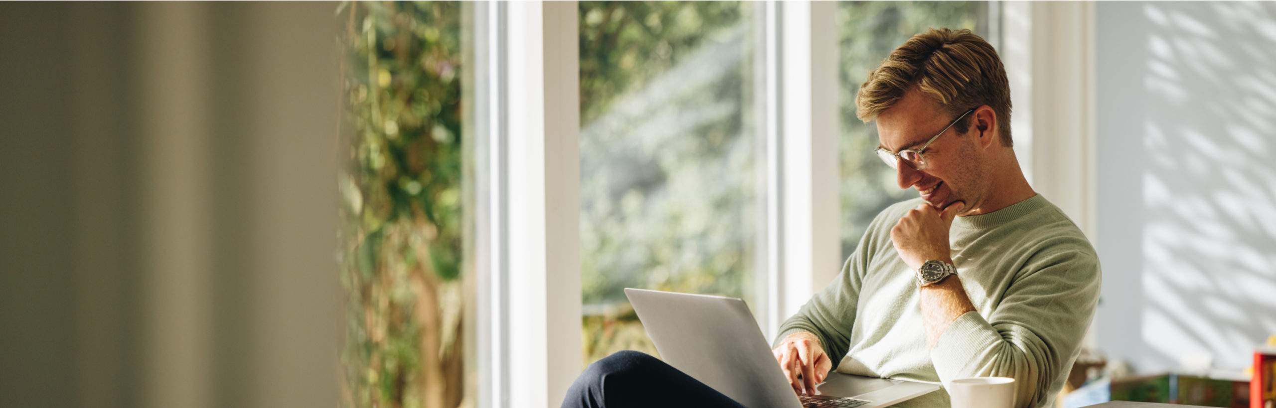 A man working on his laptop in a sunny room