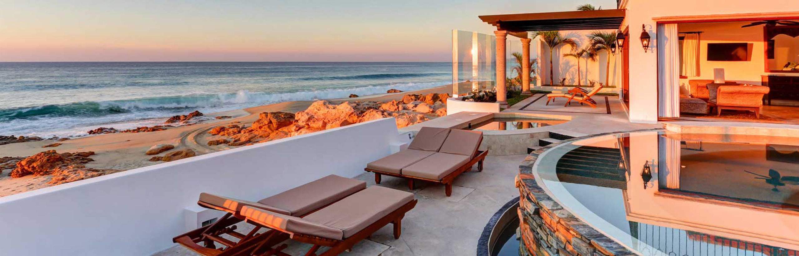 Lounge chairs by an outdoor pool at an oceanfront villa