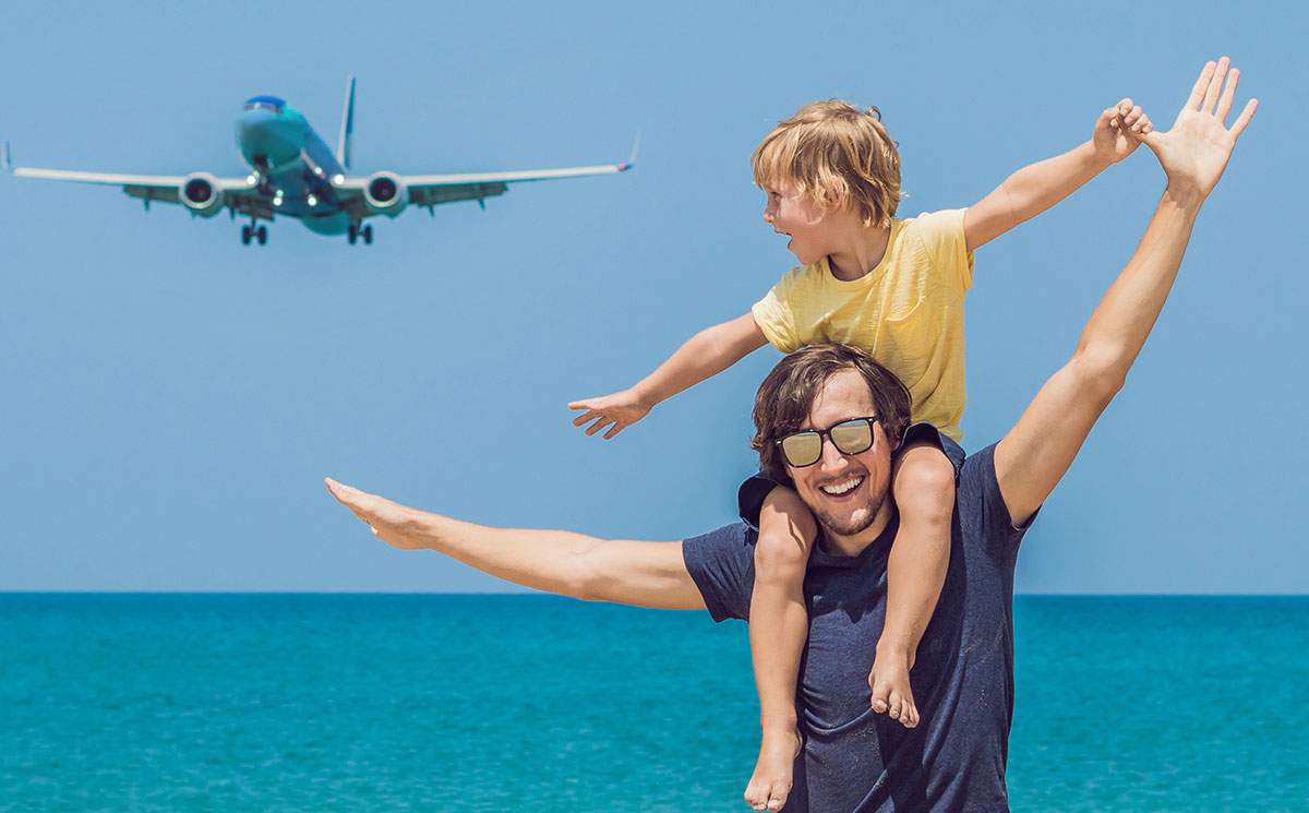 Father with son on shoulders mimicking airplane above - which is the best travel franchise?