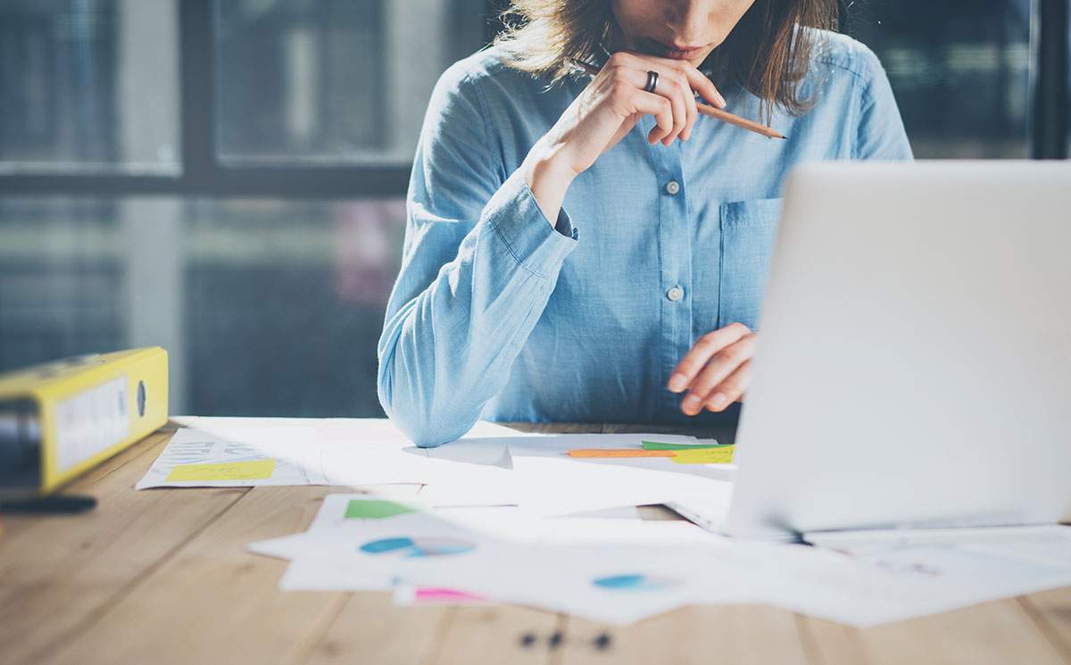 Woman looking at laptop potentially figuring out how to create a business plan for a travel agency