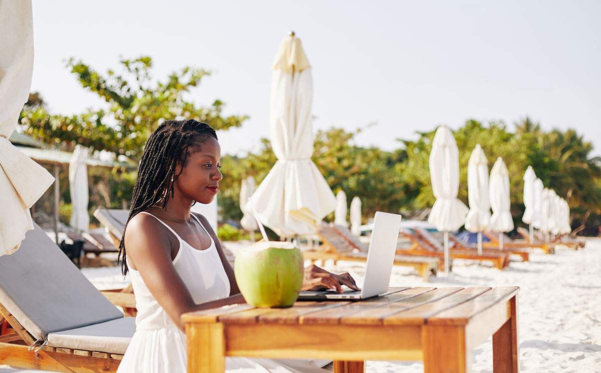 Woman working on laptop by pool - discover careers in the travel industry