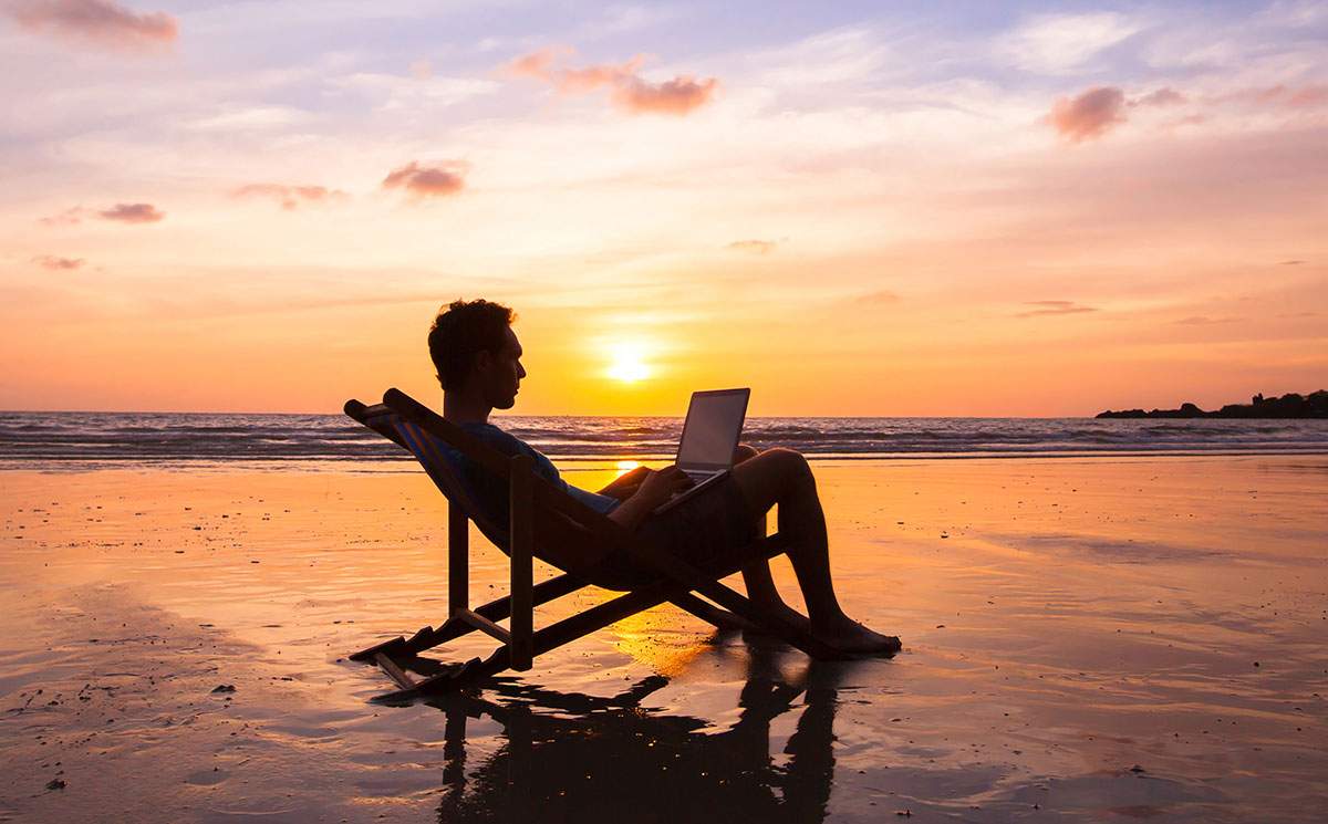 Silhouette of someone working on a laptop by the ocean - how much do franchise owners make?