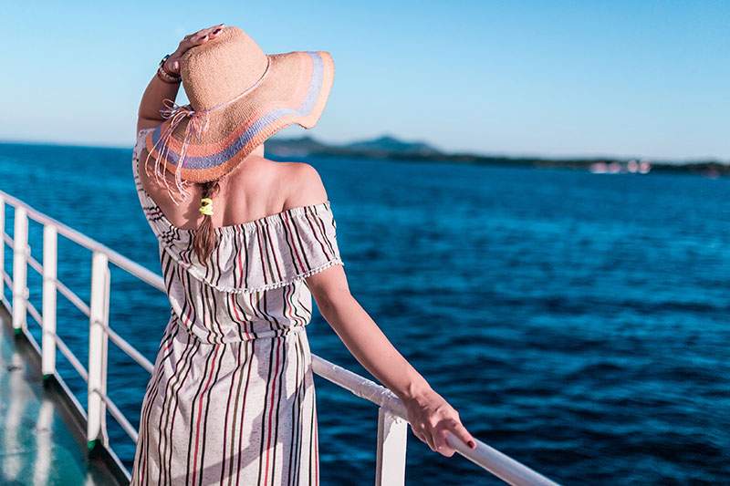 Woman in sun hat looking out to sea - what does the future of the cruise industry look like?
