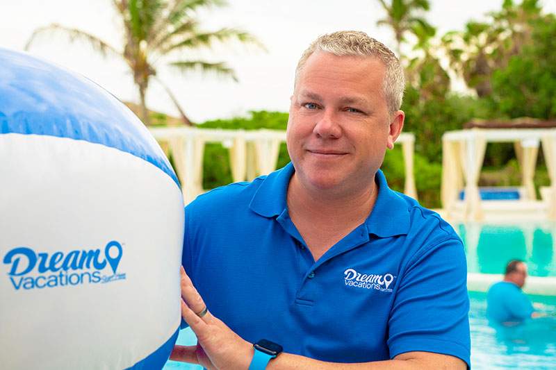 A Dream Vacations franchisee holds a branded beachball. Can you buy a franchise with no experience?