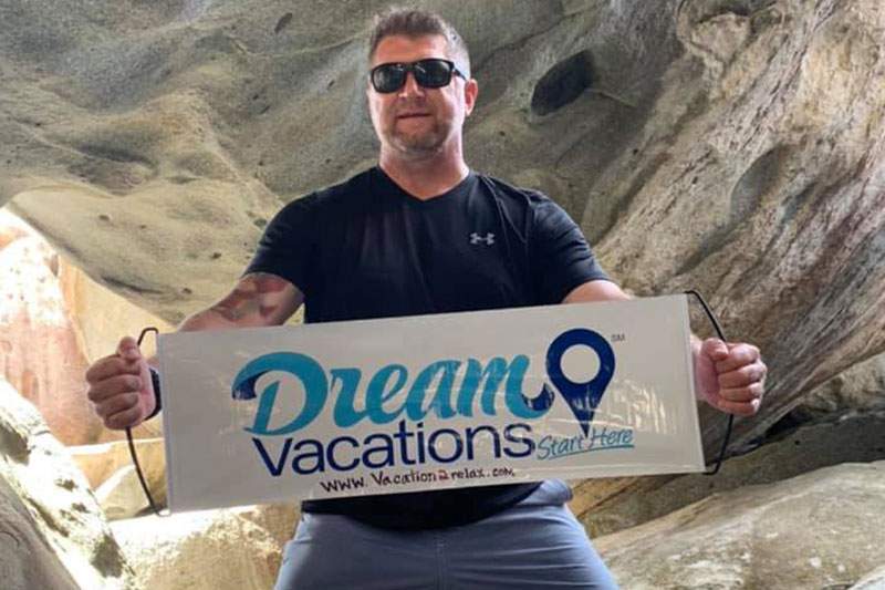 man with glasses holding dream vacations sign - financial requirements for a potential franchisee