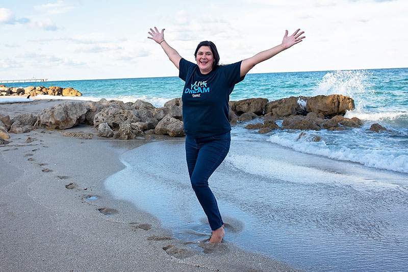 woman on beach, arms raised above her - will the cruise industry bounce back