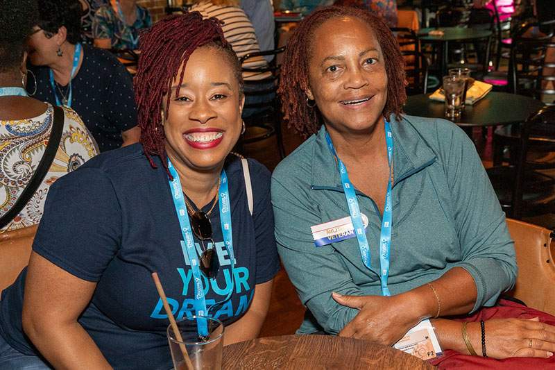 two women sit at dream vacations franchise conference table