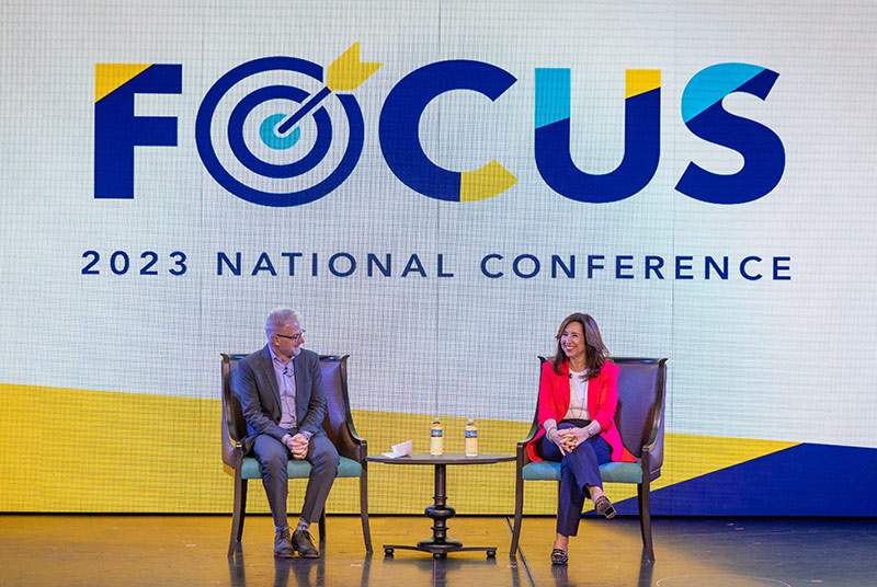 man and women sitting on stage at a national conference