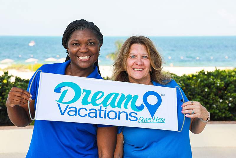 two females holding a Dream Vacations sign