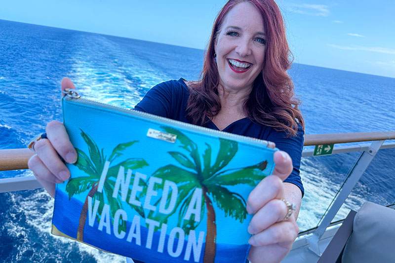 woman on a ship holding a I Need A Vacation sign