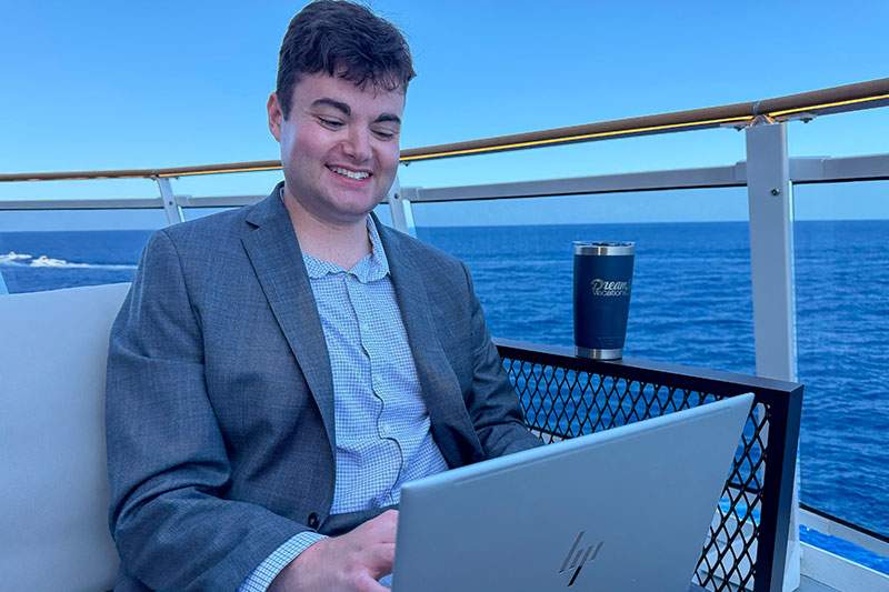 man on a ship balcony on his laptop