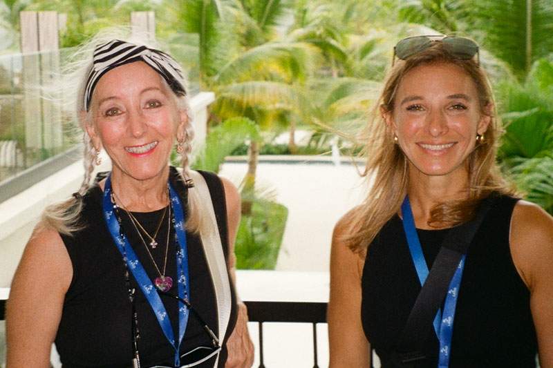 Two women smiling and standing closely together.