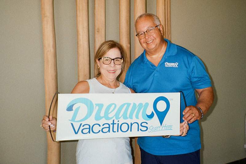 A man and woman hold a sign reading "Dream Vacations".