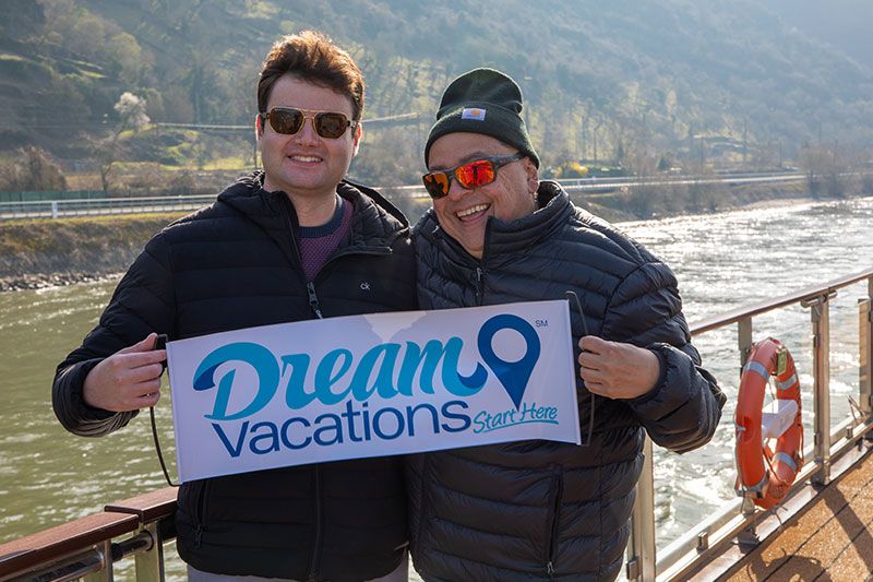 two men smiling and holding a Dream Vacations sign